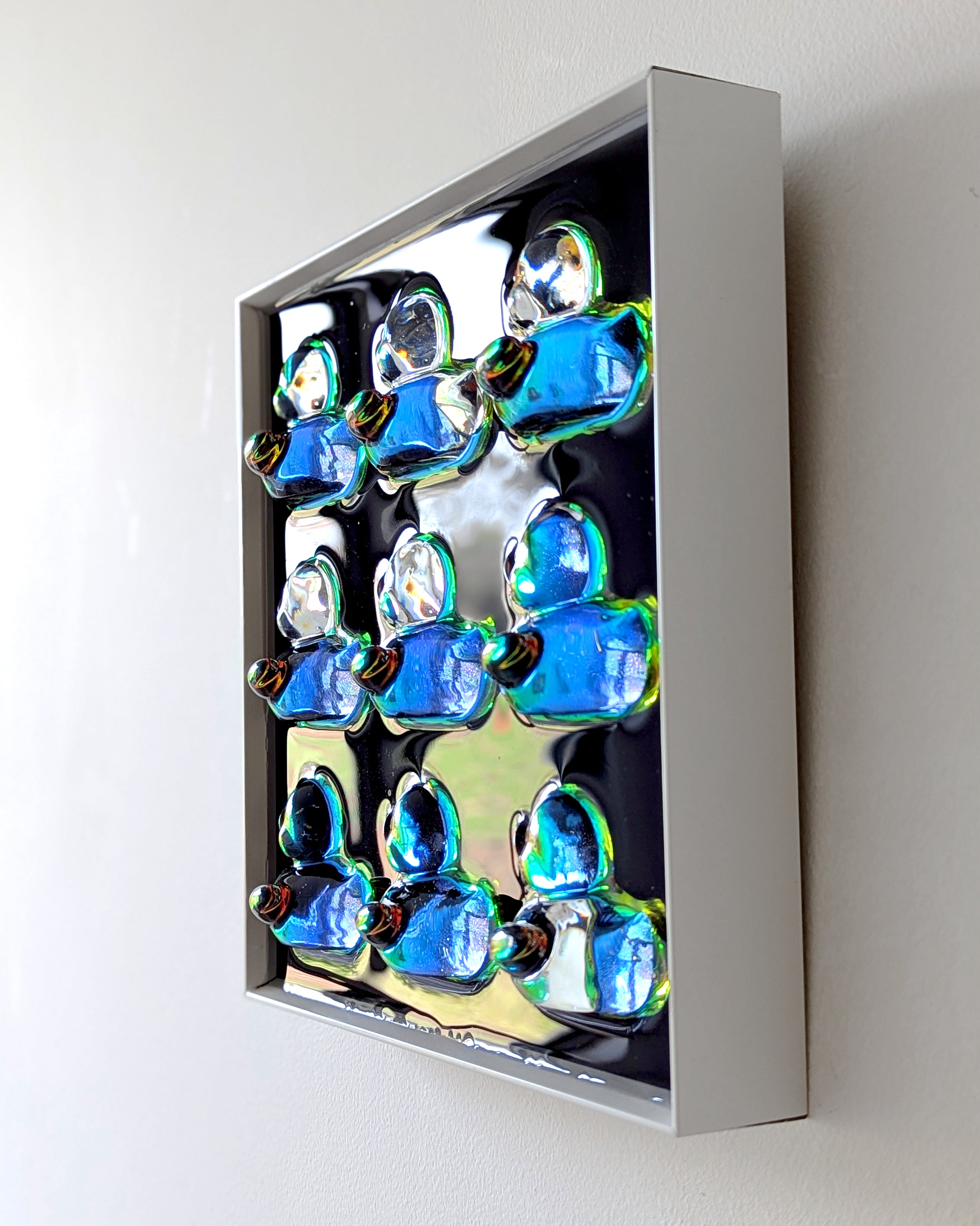 Side angle of holographic duck 3D resin wall art in frame, hanging on wall and catching light